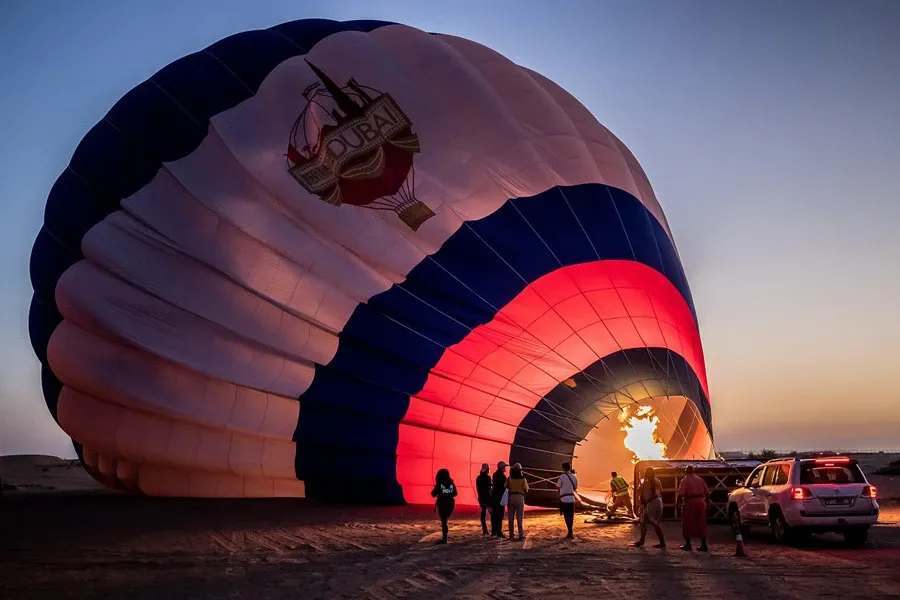 Hot air balloon envelope inflating by burner-light before dawn in the Dubai desert