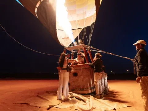 Bedouin desert camp at night with a fire performer and guests seated under a star field