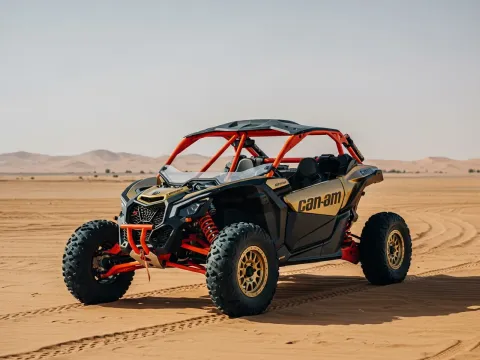 Can-Am Maverick X3 dune buggy parked on sand with helmets on the hood